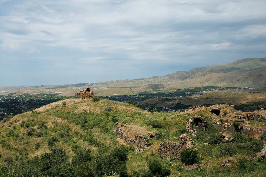 The Khosrov reserve: the monastery on a green ridge above a wide valley, with masonry remains along the slope.